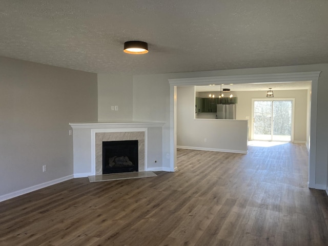 unfurnished living room featuring a premium fireplace, dark wood finished floors, and baseboards