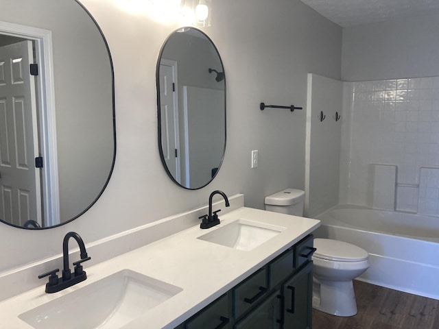 bathroom featuring double vanity, wood finished floors, a sink, and toilet