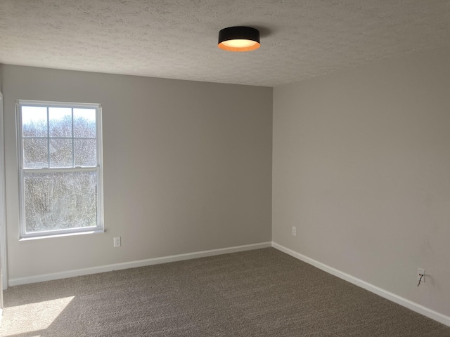 carpeted empty room featuring a textured ceiling and baseboards