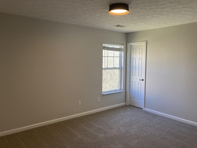 empty room with carpet, visible vents, a textured ceiling, and baseboards