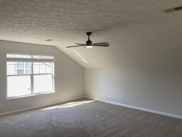 bonus room featuring a textured ceiling, carpet floors, visible vents, baseboards, and vaulted ceiling