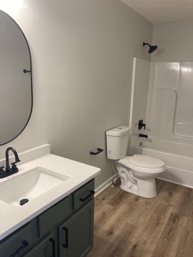 full bath with baseboards, toilet, wood finished floors, tub / shower combination, and vanity