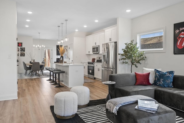 living room with baseboards, recessed lighting, light wood-type flooring, and a notable chandelier