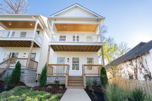 view of front of property featuring covered porch, board and batten siding, fence, and a balcony