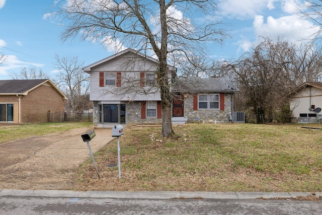 view of front of home featuring stone siding, central AC, fence, and a front lawn