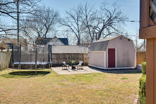 view of yard featuring a trampoline, a patio area, a fenced backyard, and an outdoor structure