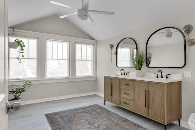 bathroom featuring lofted ceiling, double vanity, ceiling fan, and a sink