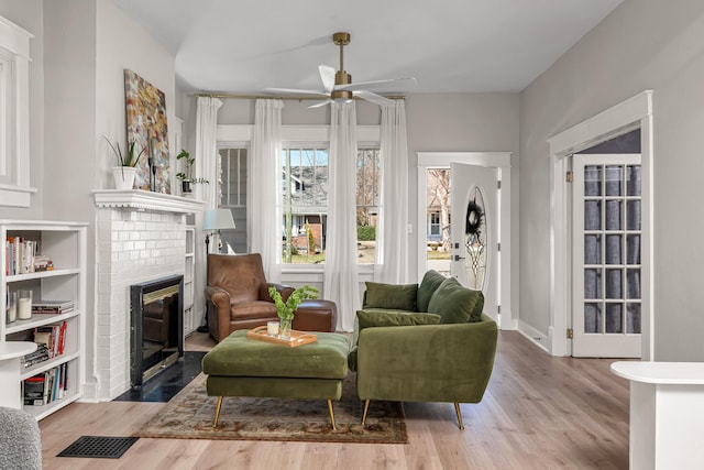 sitting room with baseboards, a fireplace, a ceiling fan, and wood finished floors