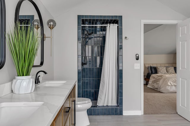 bathroom featuring lofted ceiling, double vanity, a sink, and toilet