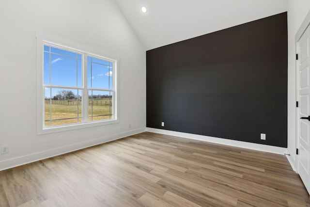 empty room with high vaulted ceiling, recessed lighting, wood finished floors, and baseboards