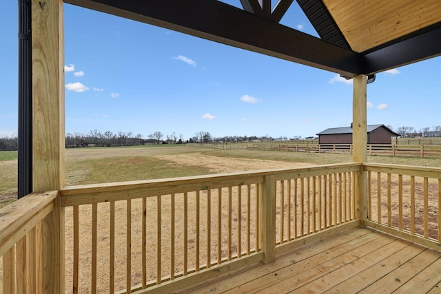 wooden terrace with a rural view, an outdoor structure, and fence