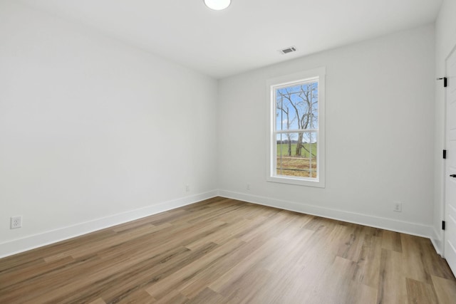 unfurnished room with light wood finished floors, visible vents, and baseboards