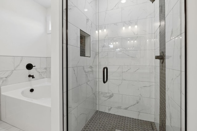 bathroom with a stall shower and a bath