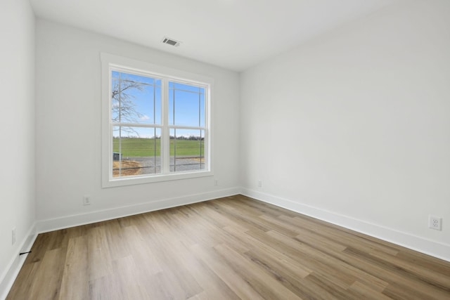 empty room with baseboards, visible vents, and wood finished floors