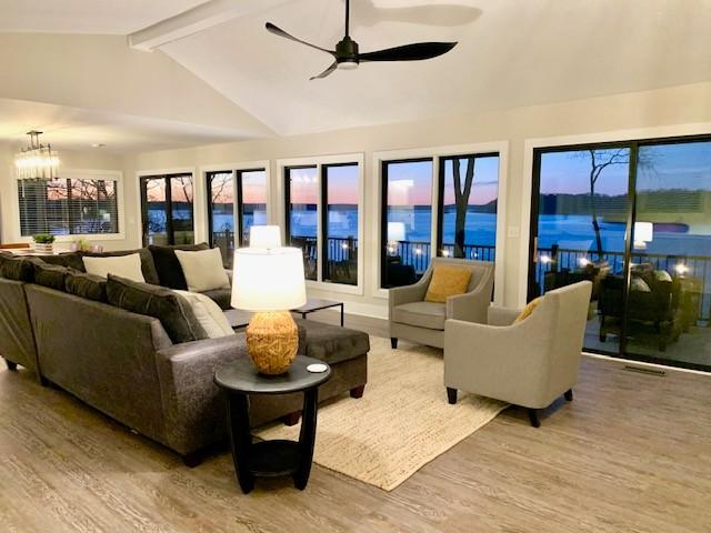 sunroom featuring vaulted ceiling with beams, ceiling fan with notable chandelier, and visible vents