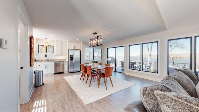 dining area with light wood-style floors, recessed lighting, and an inviting chandelier