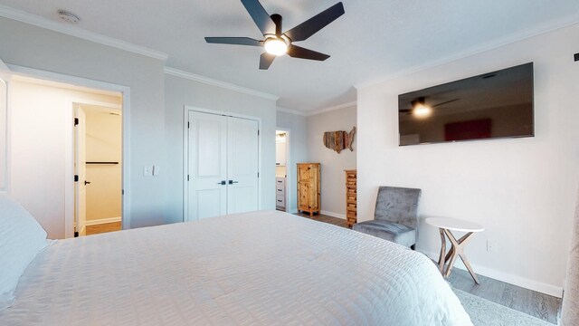 bedroom featuring crown molding, a closet, baseboards, and wood finished floors