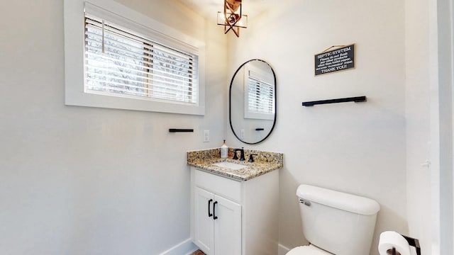 half bathroom with vanity, toilet, and baseboards