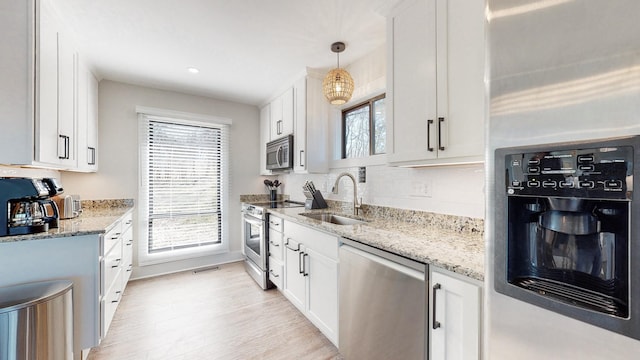 kitchen featuring visible vents, appliances with stainless steel finishes, light stone countertops, white cabinetry, and a sink