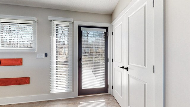 doorway to outside with light wood-type flooring and baseboards