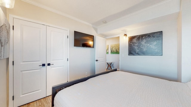 bedroom with light wood-style floors, a closet, and crown molding