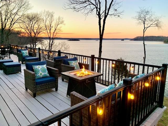 deck with a water view and an outdoor living space with a fire pit