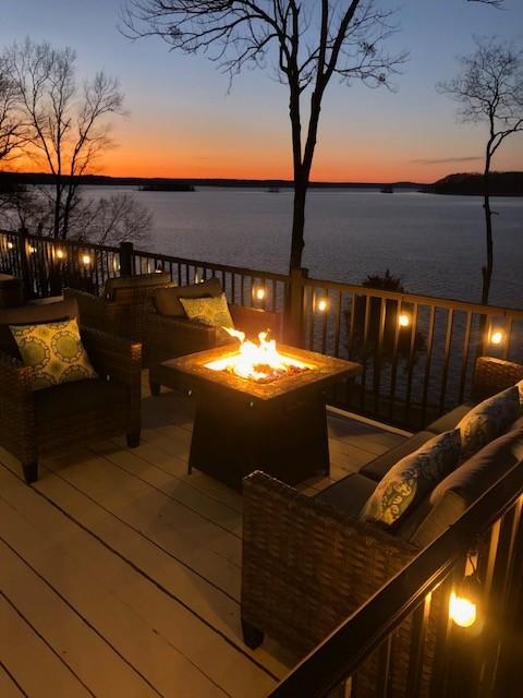 deck at dusk with a water view and a fire pit