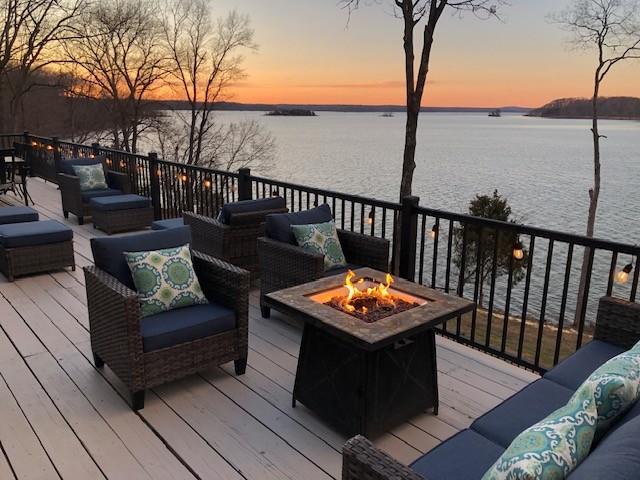 deck with an outdoor living space with a fire pit and a water view