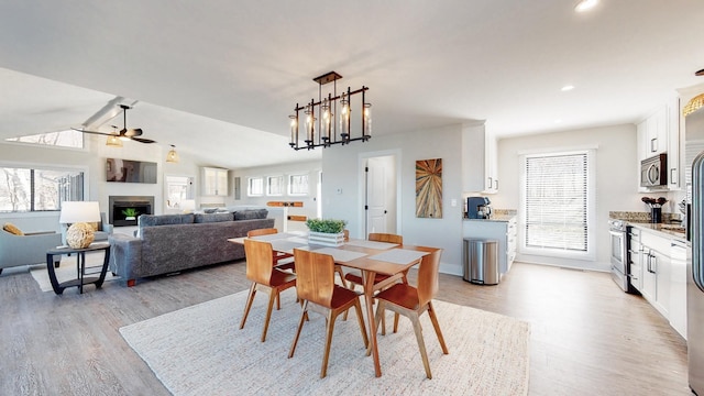 dining room featuring lofted ceiling, ceiling fan, light wood-style floors, a fireplace, and recessed lighting