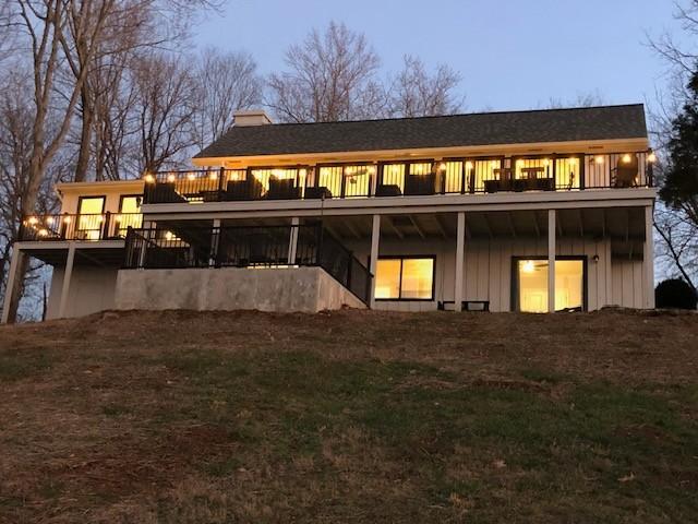 rear view of house featuring a deck, board and batten siding, and a chimney