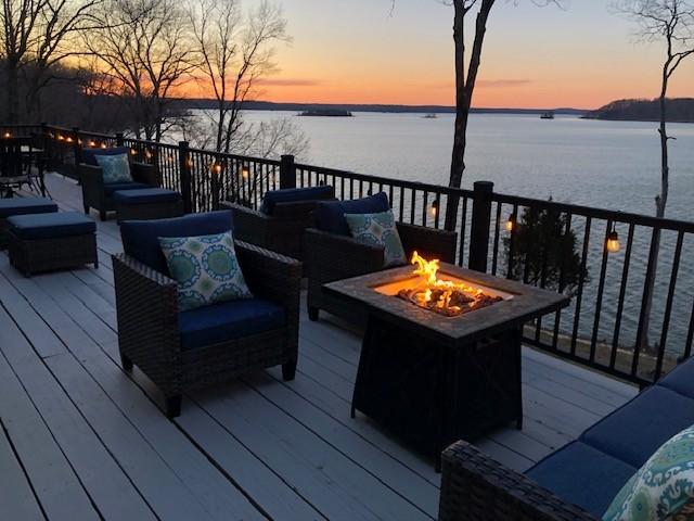 deck with a water view and an outdoor living space with a fire pit