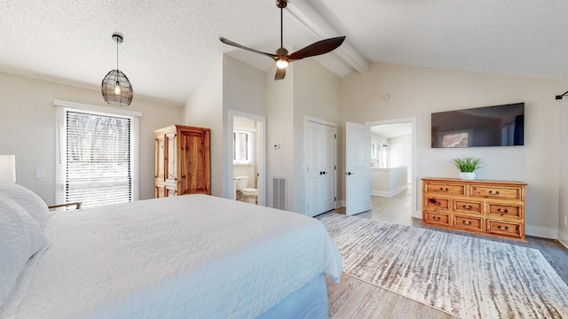 bedroom with visible vents, lofted ceiling with beams, ensuite bathroom, a textured ceiling, and wood finished floors