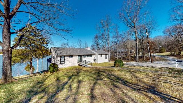 back of house featuring a chimney and a lawn