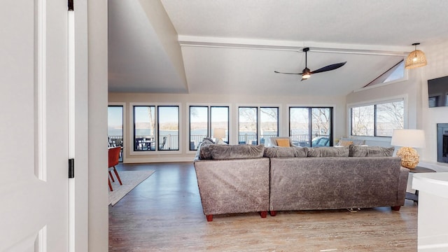 living room with vaulted ceiling with beams, light wood finished floors, a fireplace, and a ceiling fan