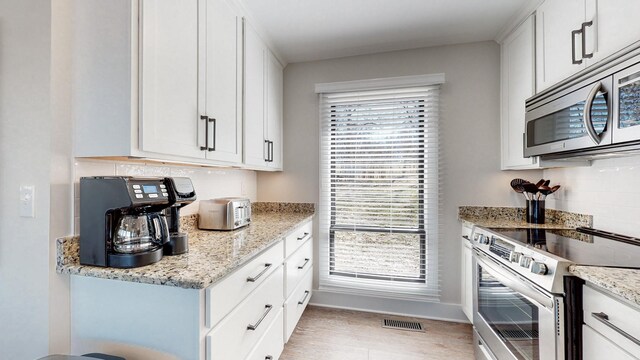 kitchen with light stone counters, tasteful backsplash, visible vents, appliances with stainless steel finishes, and white cabinetry