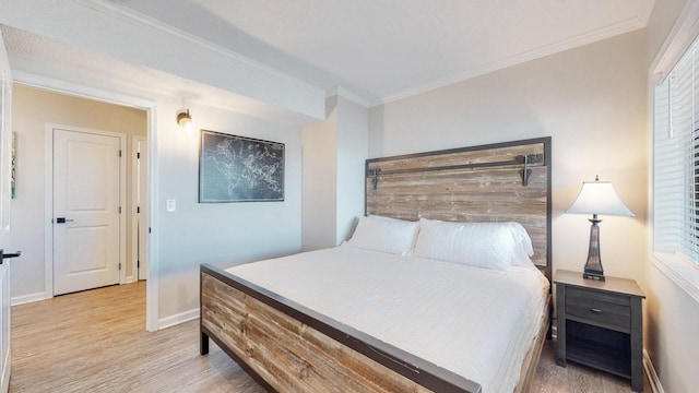 bedroom featuring light wood finished floors, baseboards, and ornamental molding