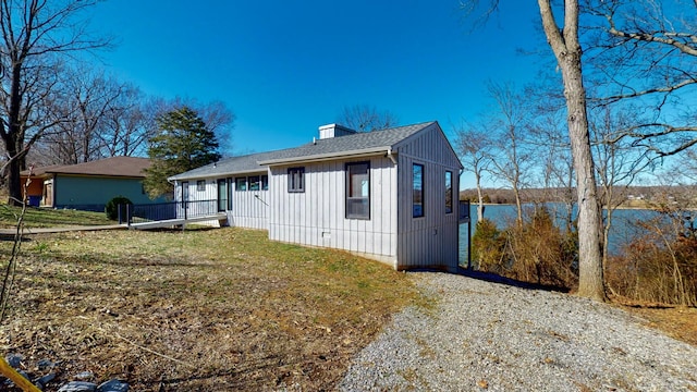 view of front of home featuring driveway, a shingled roof, a chimney, and board and batten siding