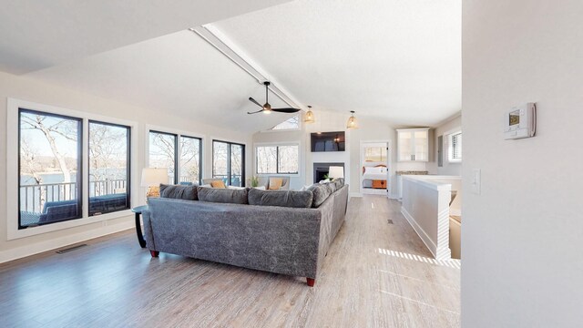 living area with light wood-style floors, baseboards, a fireplace, and visible vents