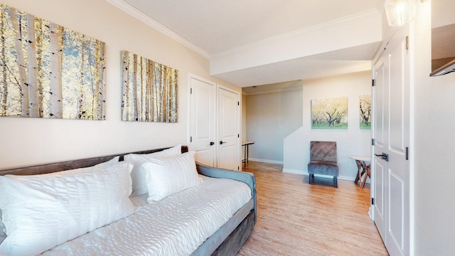 bedroom with ornamental molding, light wood-type flooring, and baseboards