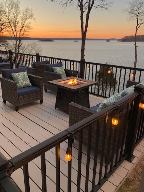 wooden deck featuring a water view and an outdoor fire pit