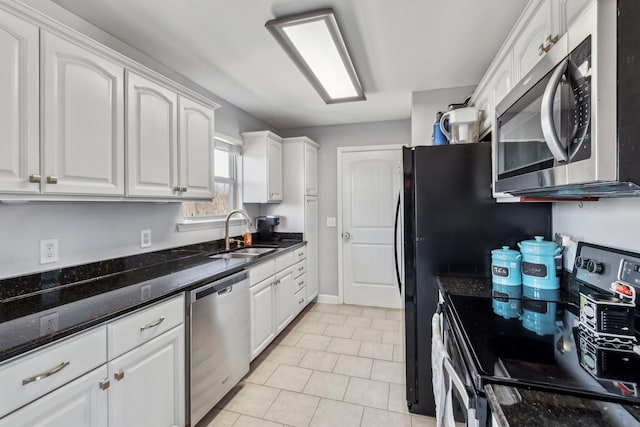 kitchen featuring light tile patterned floors, dark stone counters, a sink, stainless steel appliances, and white cabinets