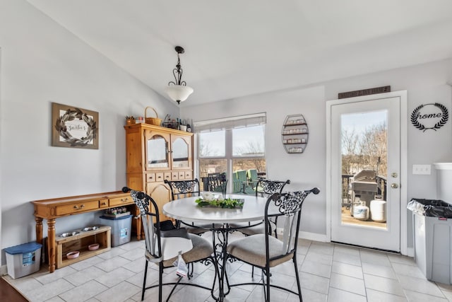 dining space featuring lofted ceiling, light tile patterned flooring, and baseboards