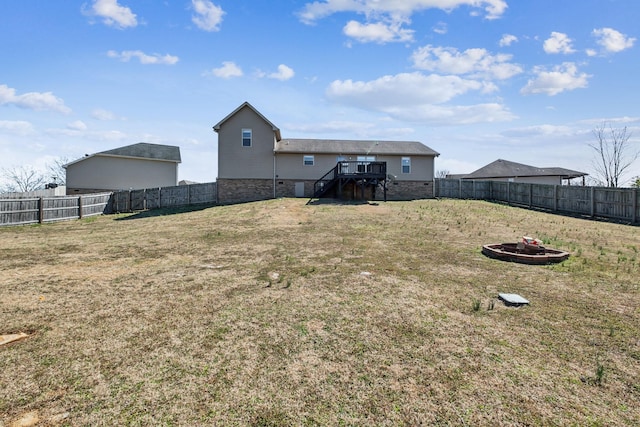 view of yard featuring a deck, stairway, a fenced backyard, and an outdoor fire pit