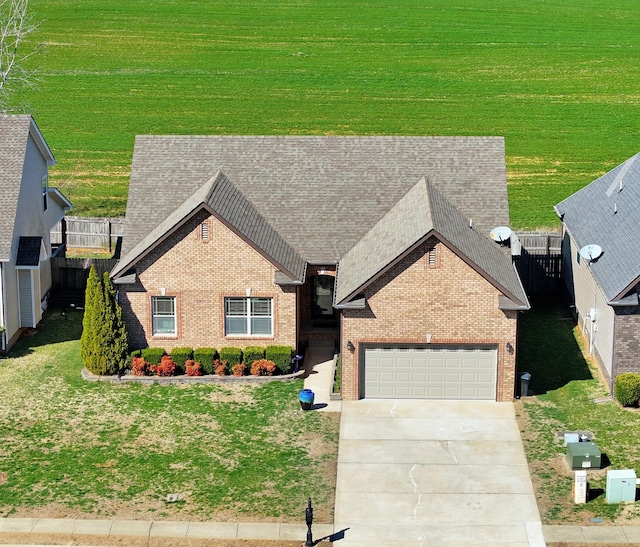 view of front of house featuring a front yard, roof with shingles, concrete driveway, a garage, and brick siding