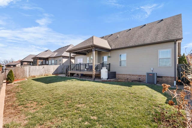 rear view of house featuring roof with shingles, a yard, a fenced backyard, central AC, and a deck