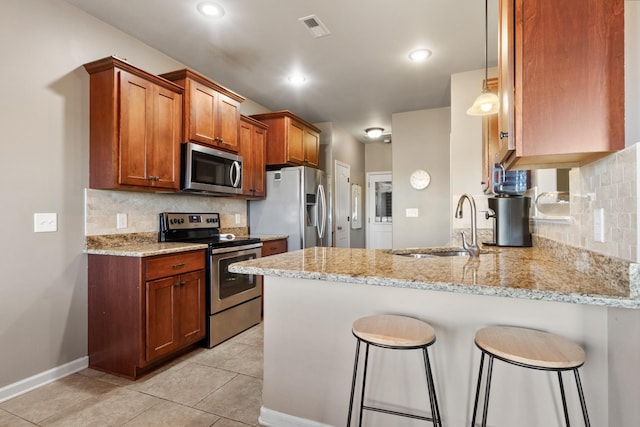 kitchen with light stone counters, visible vents, a peninsula, a sink, and stainless steel appliances