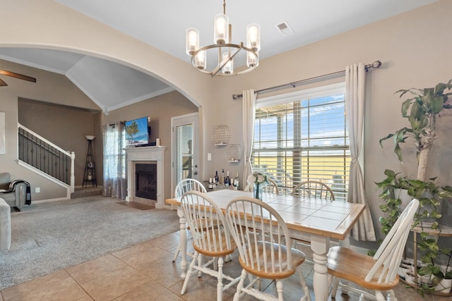 dining space featuring light carpet, a fireplace with flush hearth, light tile patterned floors, stairs, and vaulted ceiling