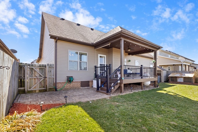 rear view of house with a lawn, a gate, a fenced backyard, roof with shingles, and a patio area