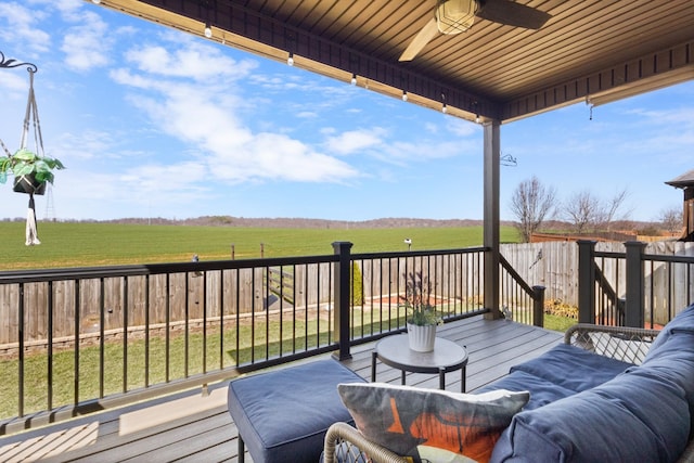 deck with a rural view, an outdoor hangout area, a ceiling fan, and fence