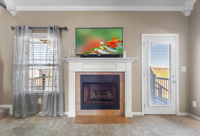 unfurnished living room featuring a tiled fireplace, carpet flooring, baseboards, and ornamental molding